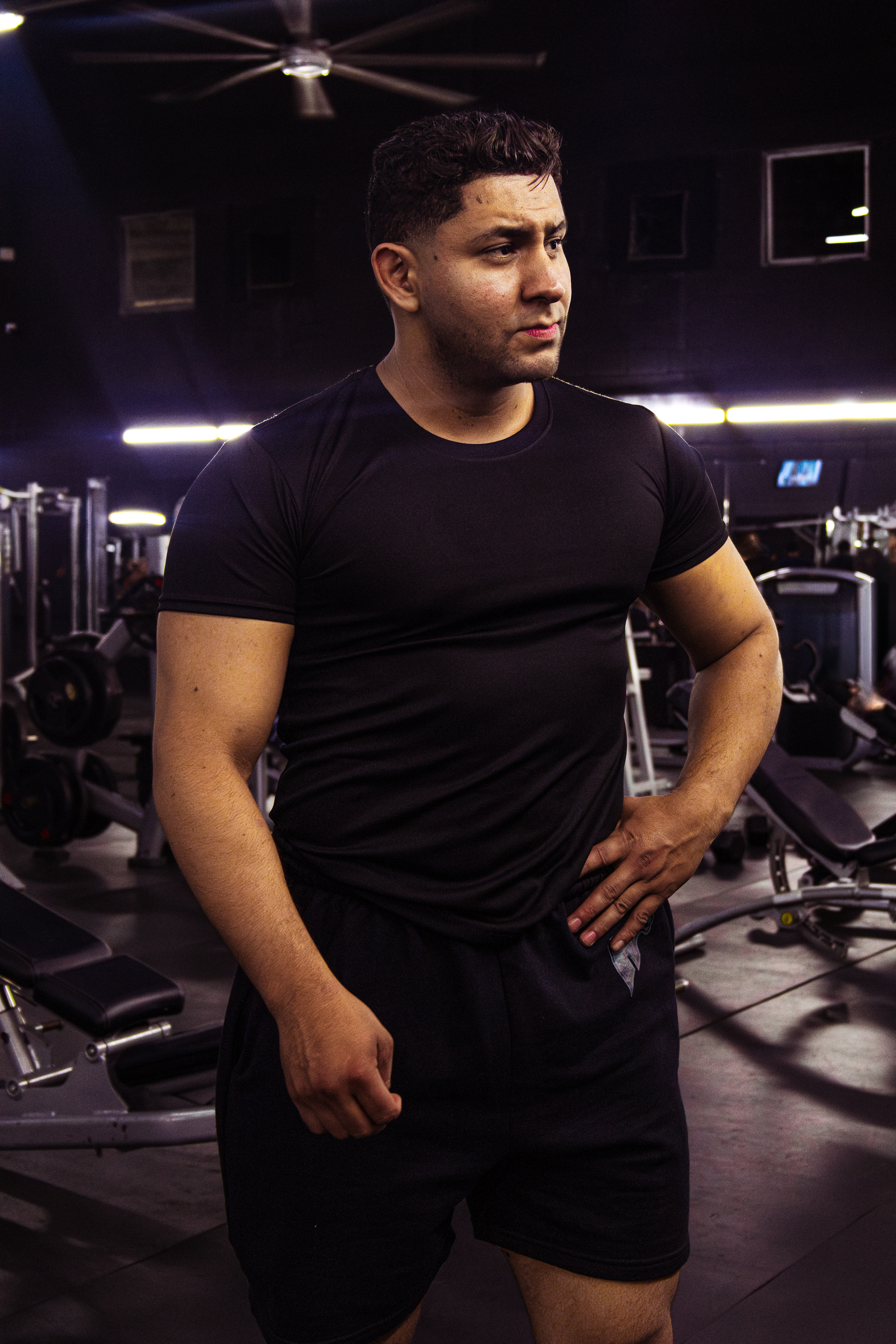 Atleta Hustform de pie bajo la iluminación del gimnasio con camiseta deportiva negra