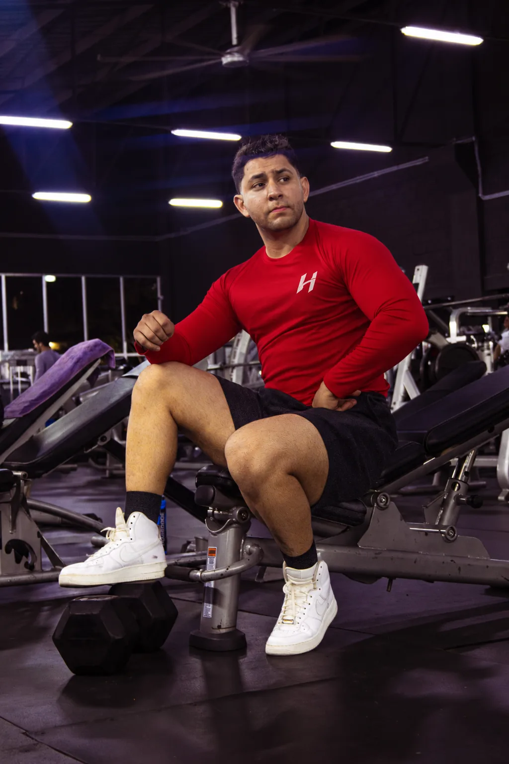 Atleta Hustform sentado en un banco de gimnasio con camiseta roja de manga larga
