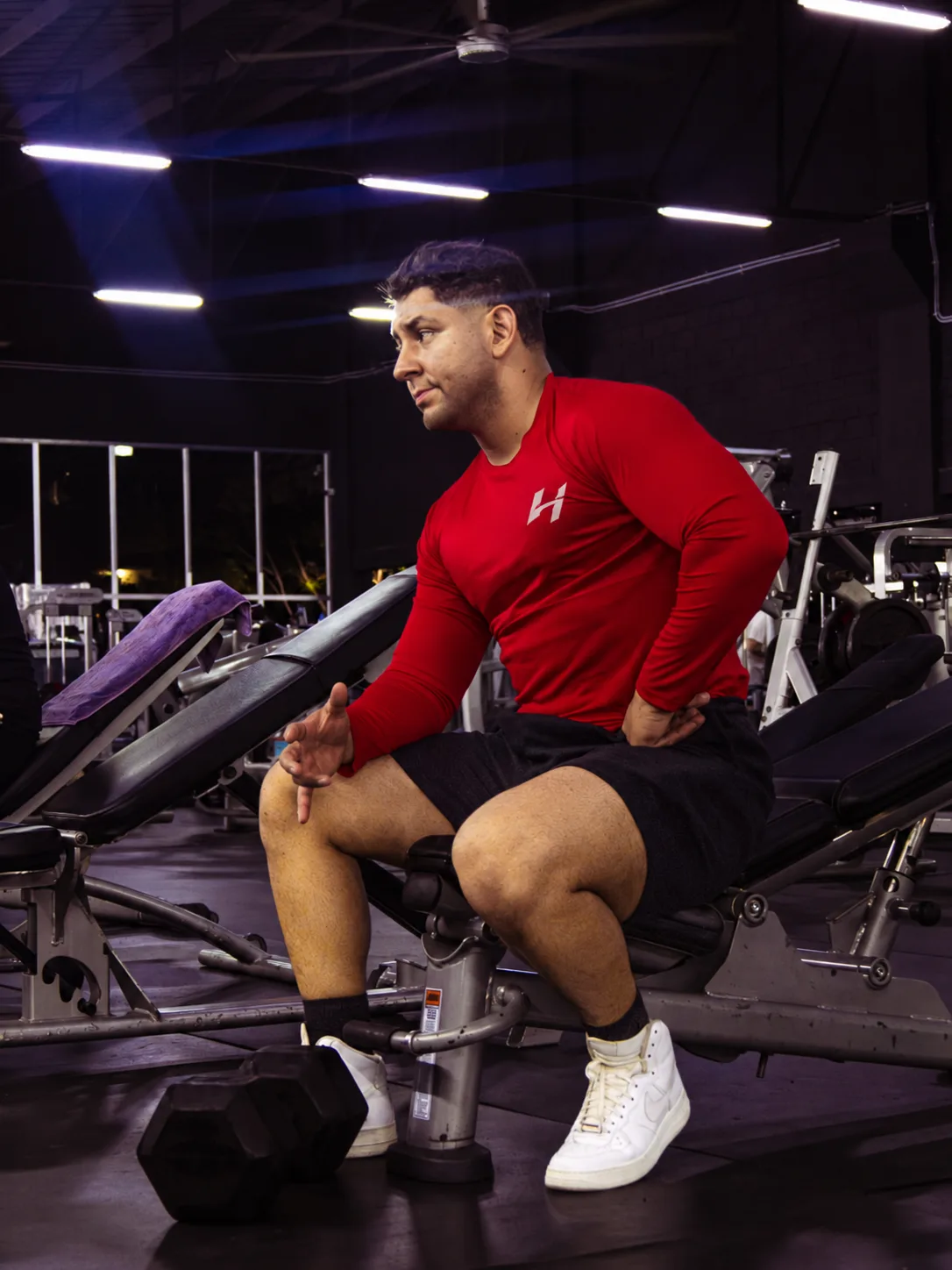 Atleta Hustform con camiseta roja de manga larga caminando por el gimnasio